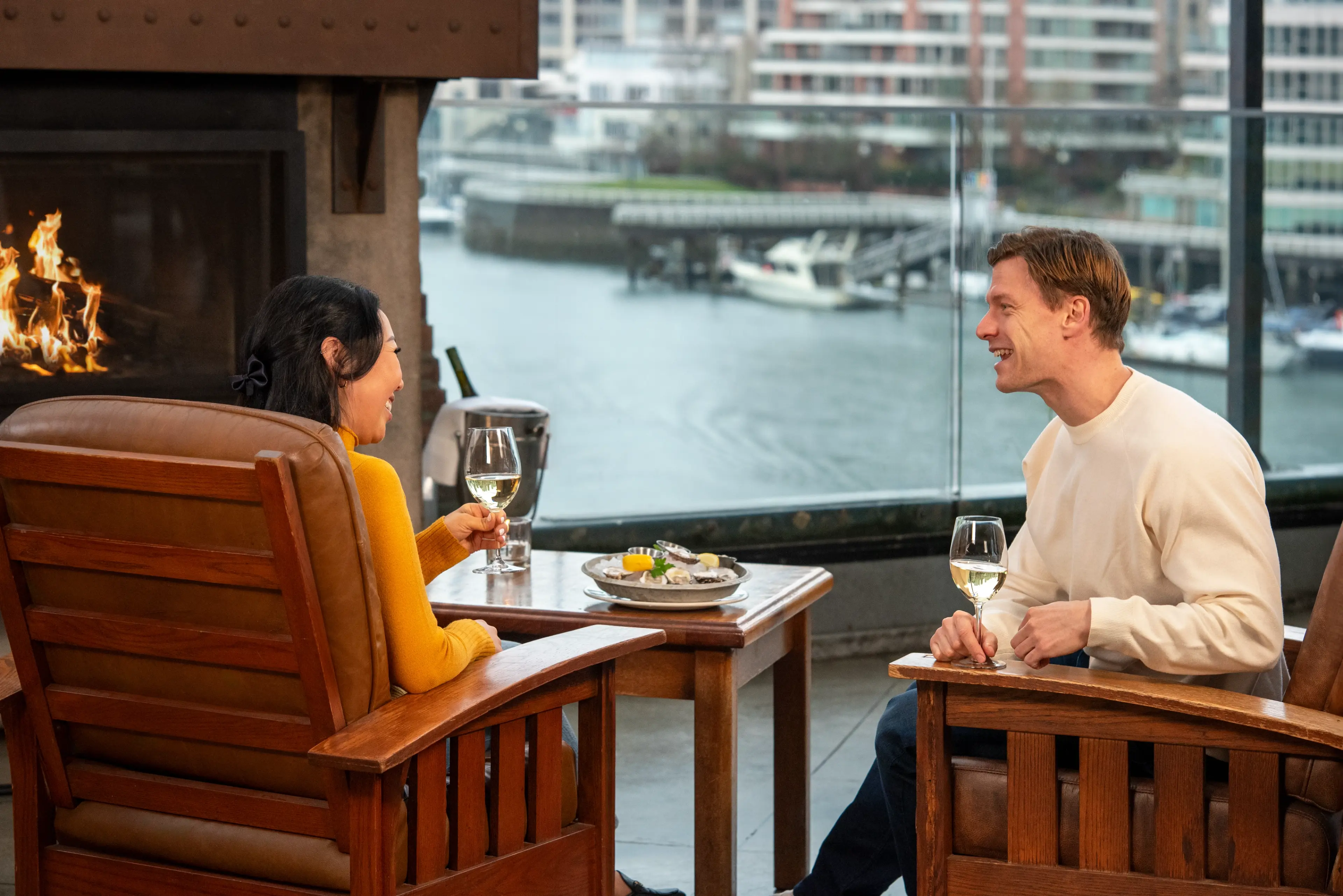 Two people sitting in front of a fireplace enjoying a glas of wine at the Sandbar restaurant on Granville Island, Vancouver.