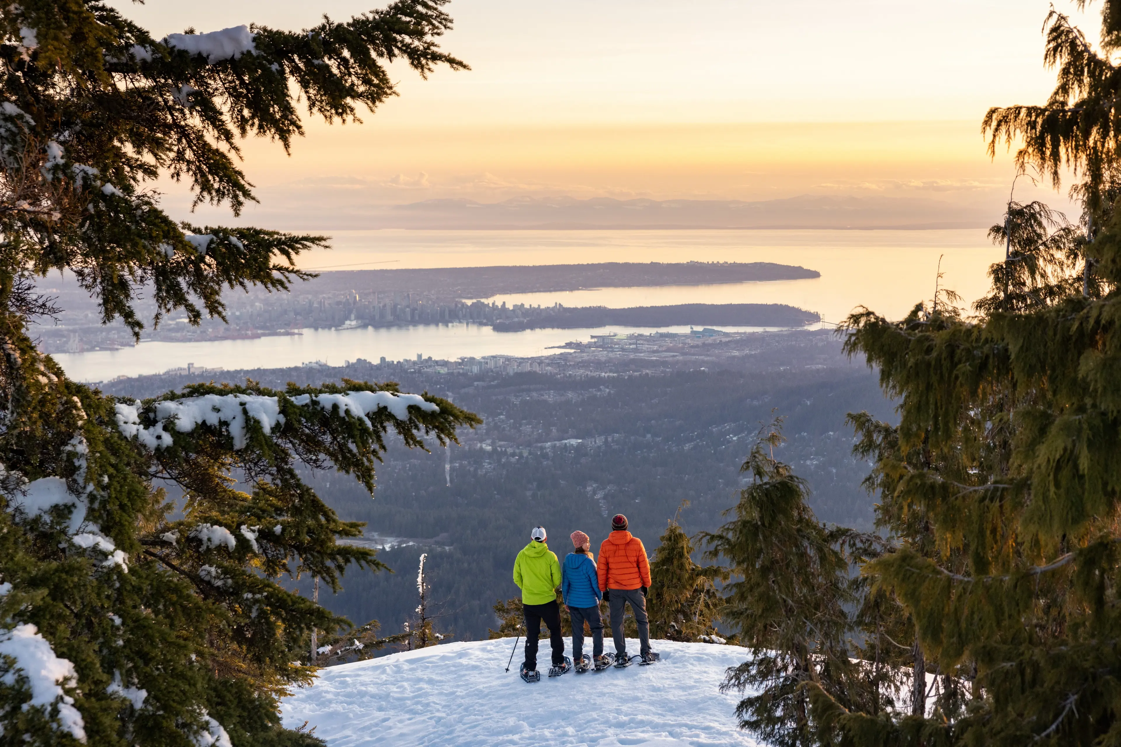 Three people snowshoeing at Mount Seymour with a view of Vancouver