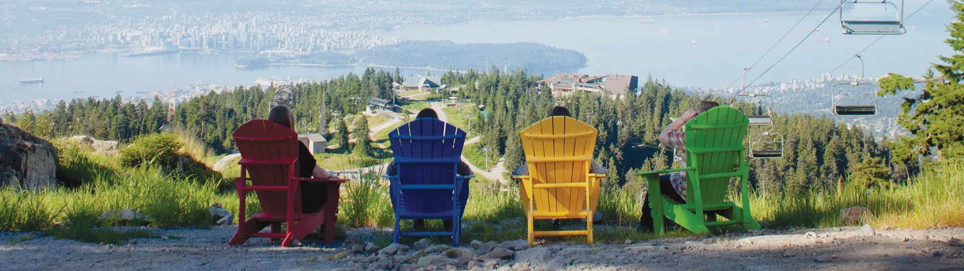 People sit in colourful chairs to enjoy the view on top of Grouse Mountain in Vancouver