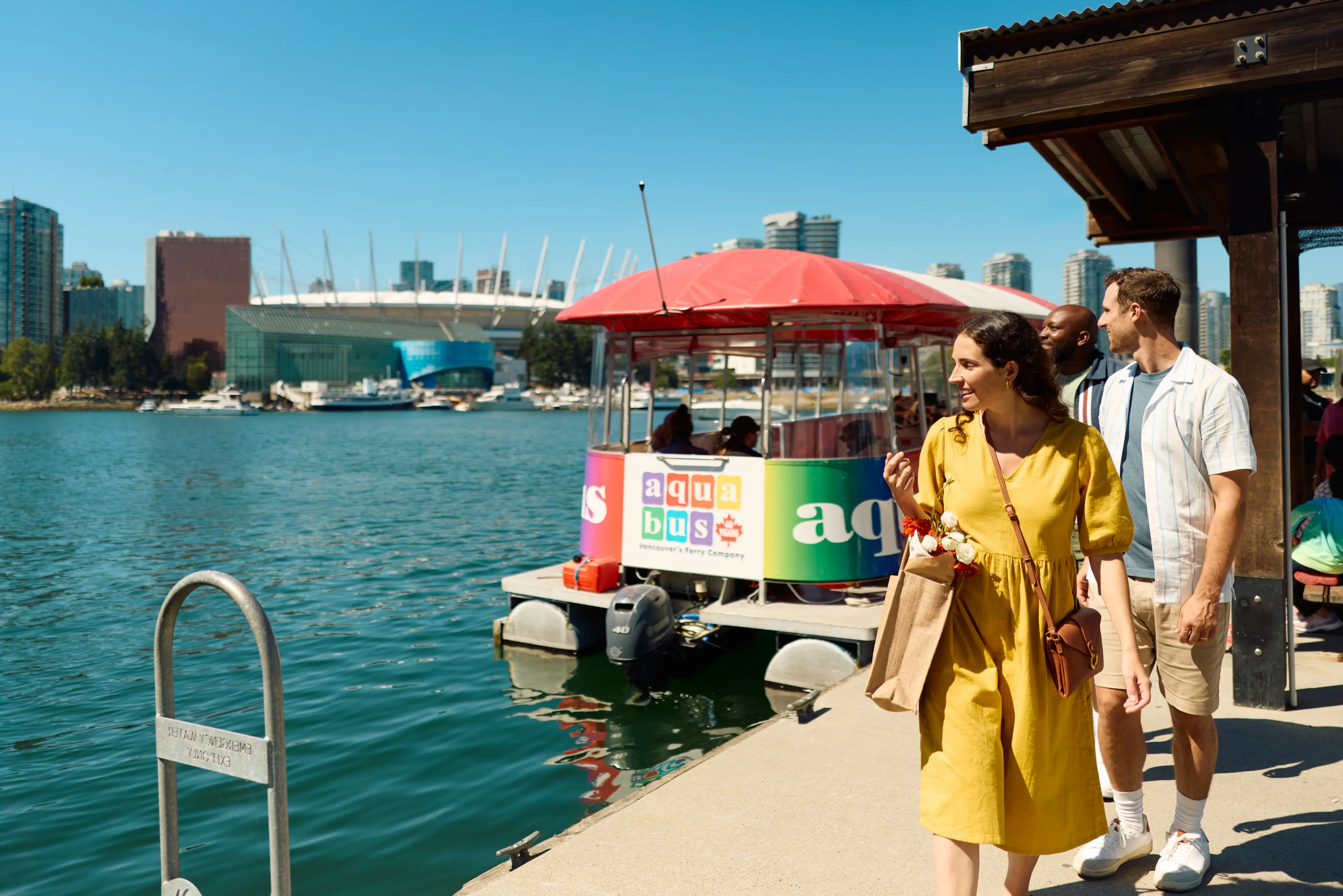 Two people coming off from the Aquabus with BC Place in the background in Vancouver.