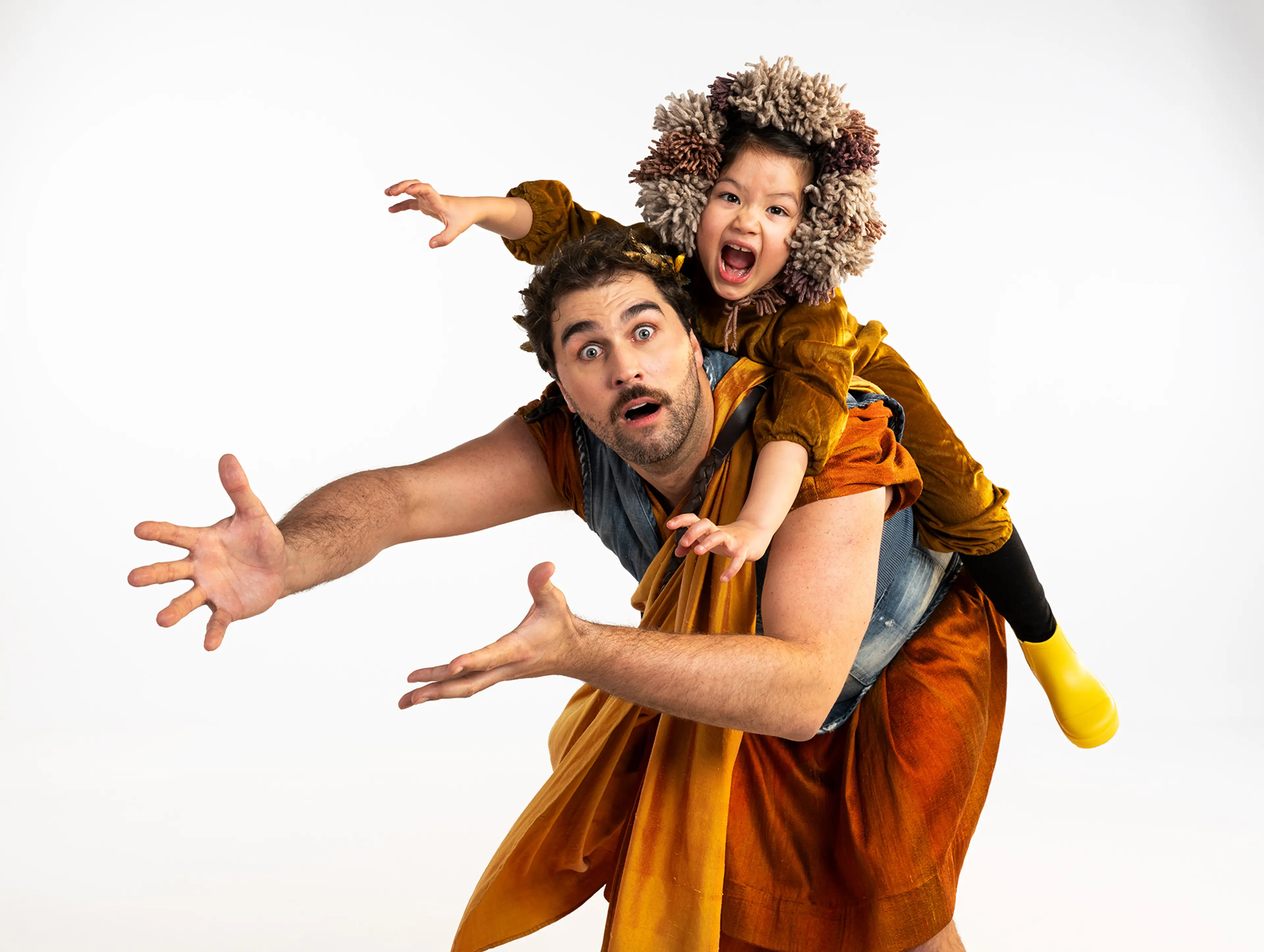 A person with a surprised expression carrying a child wearing a furry hood and yellow boots on their back, both reaching forward.