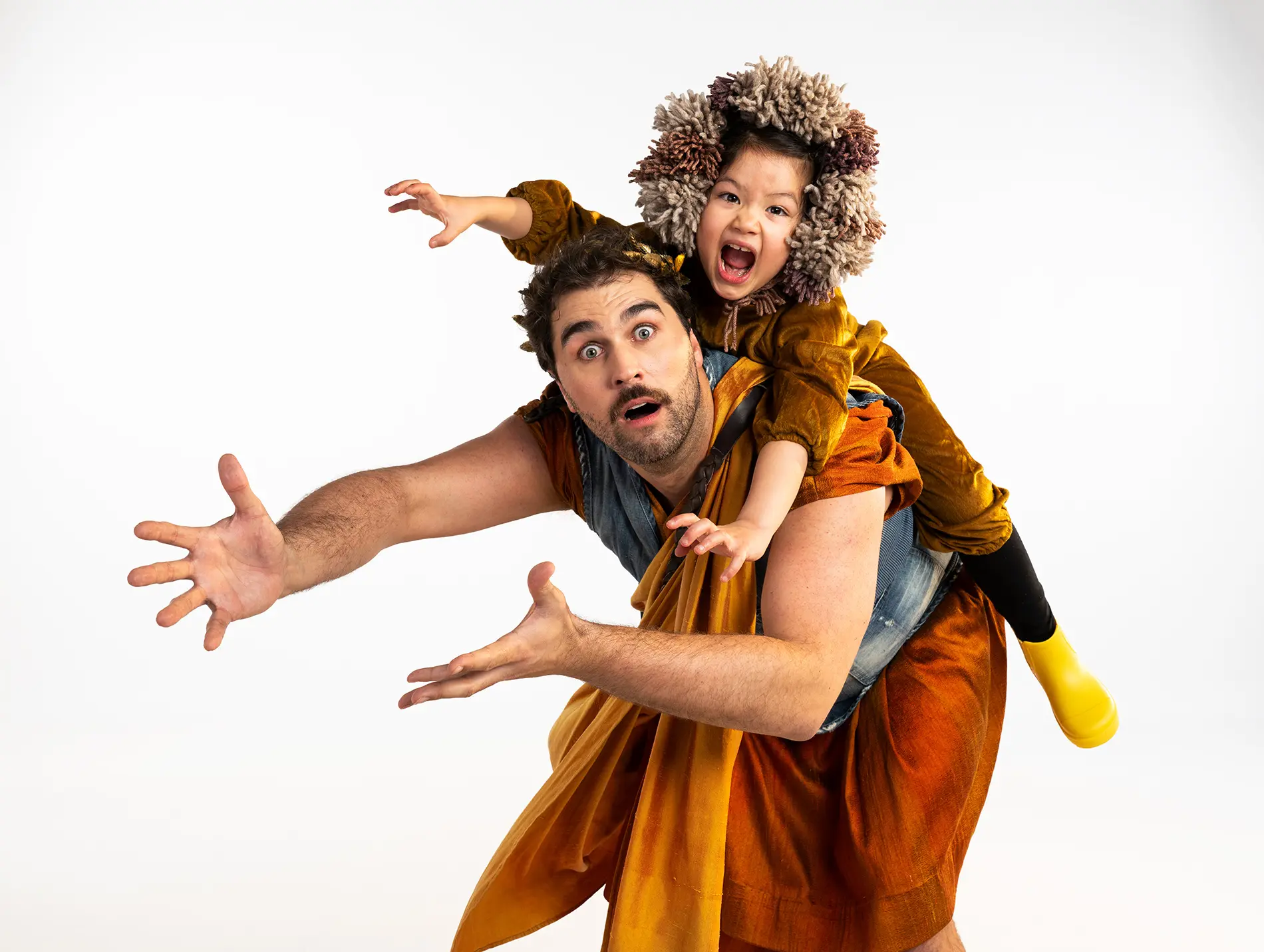 A person with a surprised expression carrying a child wearing a furry hood and yellow boots on their back, both reaching forward.