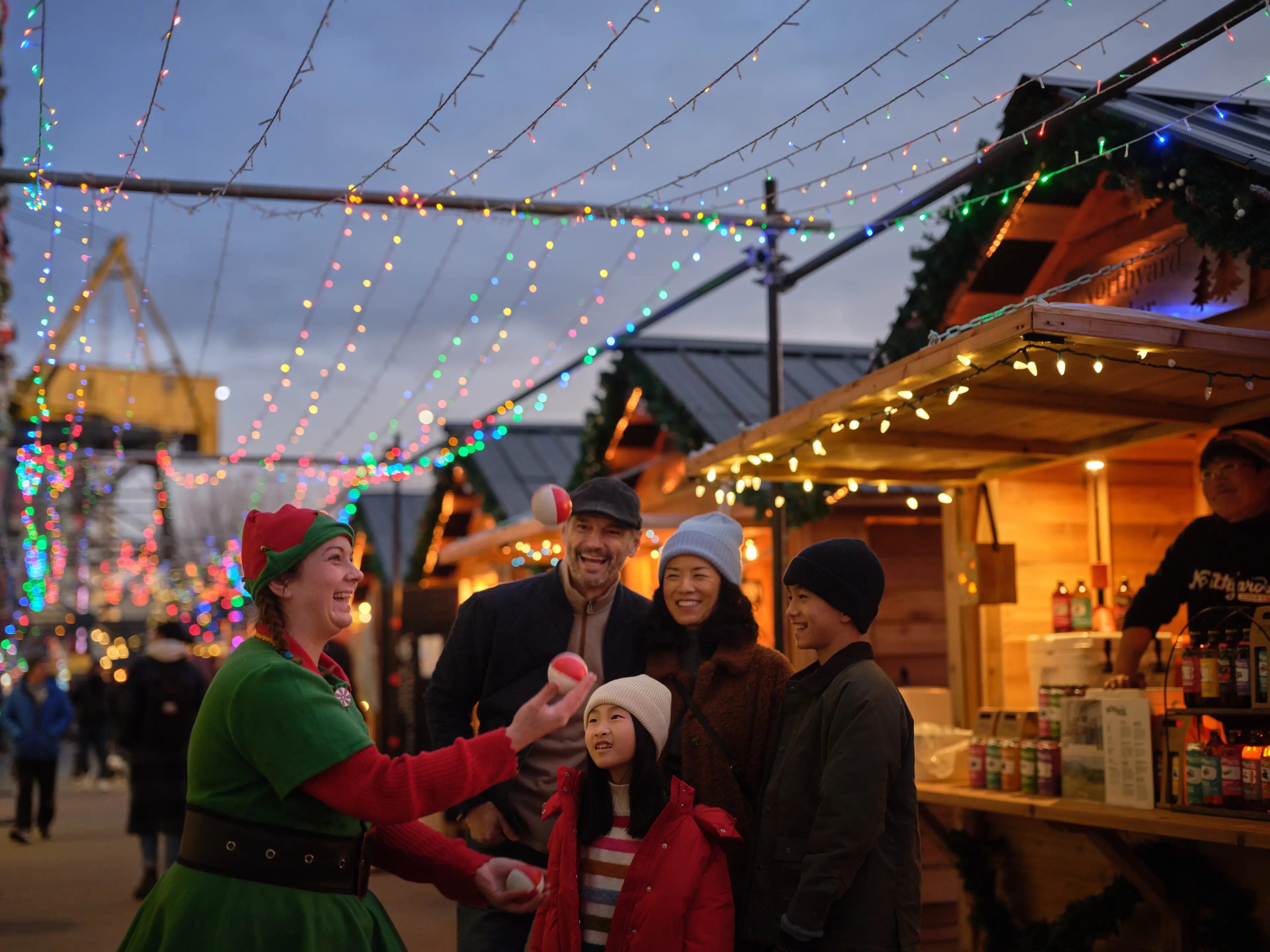 A family watching a juggler at the North Vancouver Shipyards Christmas Market.