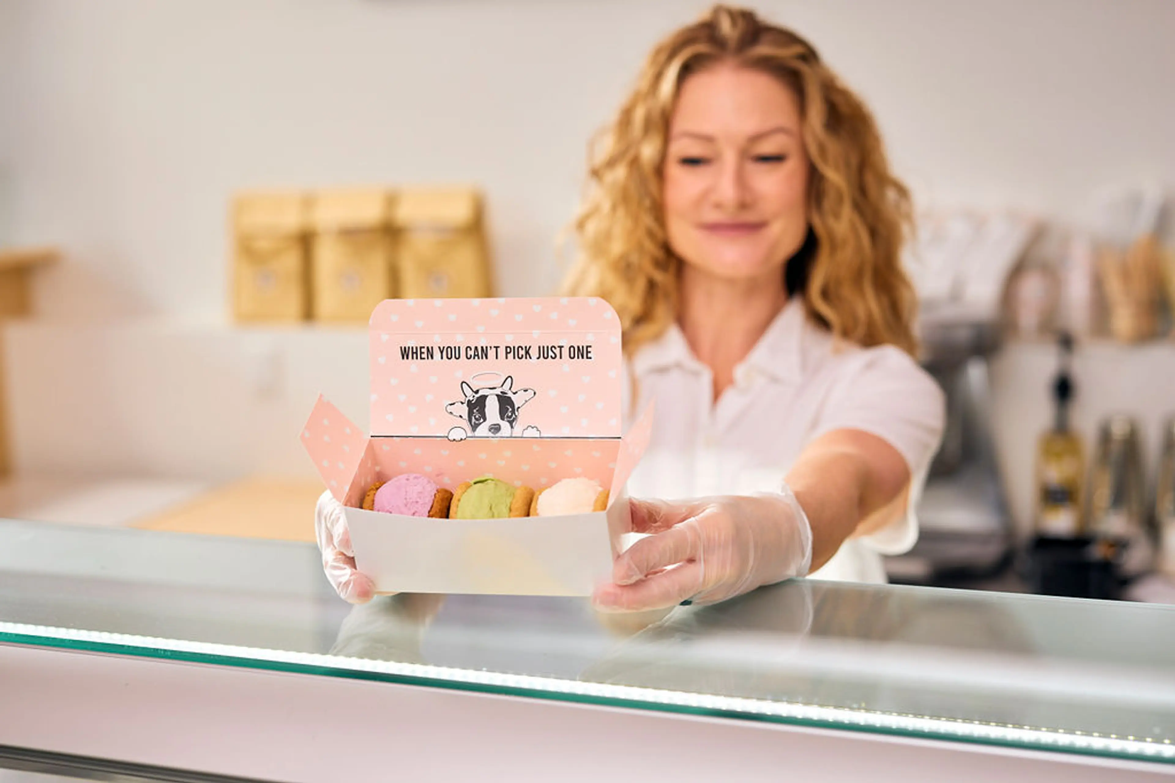 A person standing at the ice cream counter holding a box of ice cream sandwiches at Innocent Ice Cream Parlour.