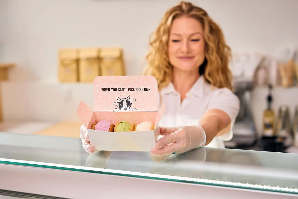 A person standing at the ice cream counter holding a box of ice cream sandwiches at Innocent Ice Cream Parlour.