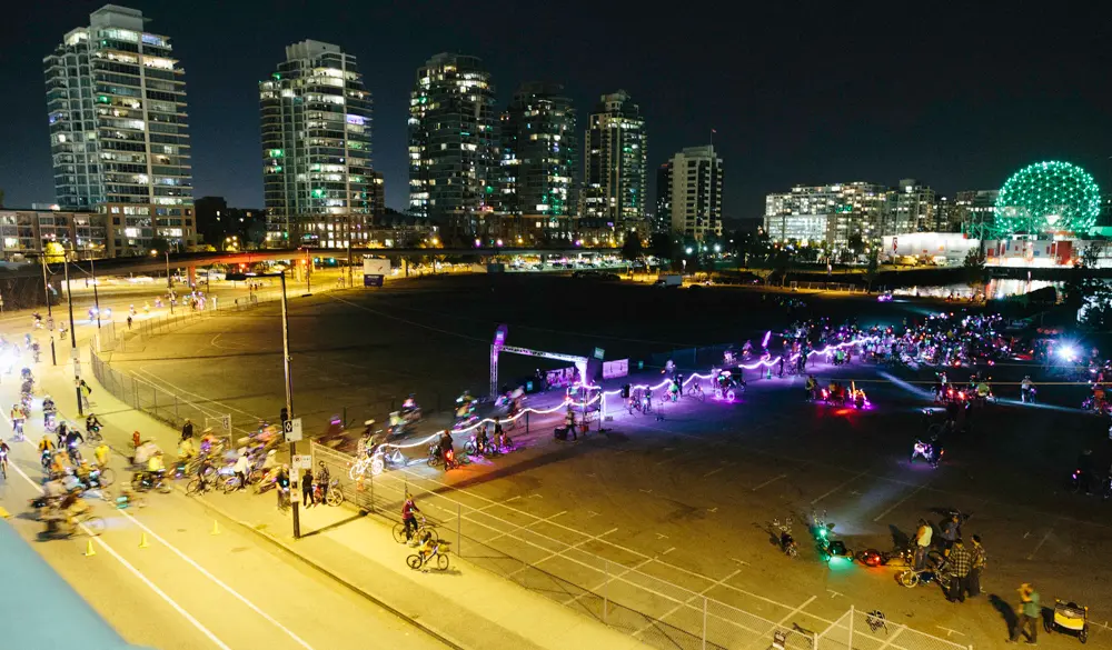 A large group of cyclists wearing colourful lights bikes at the Bike the Night event in Vancouver, BC