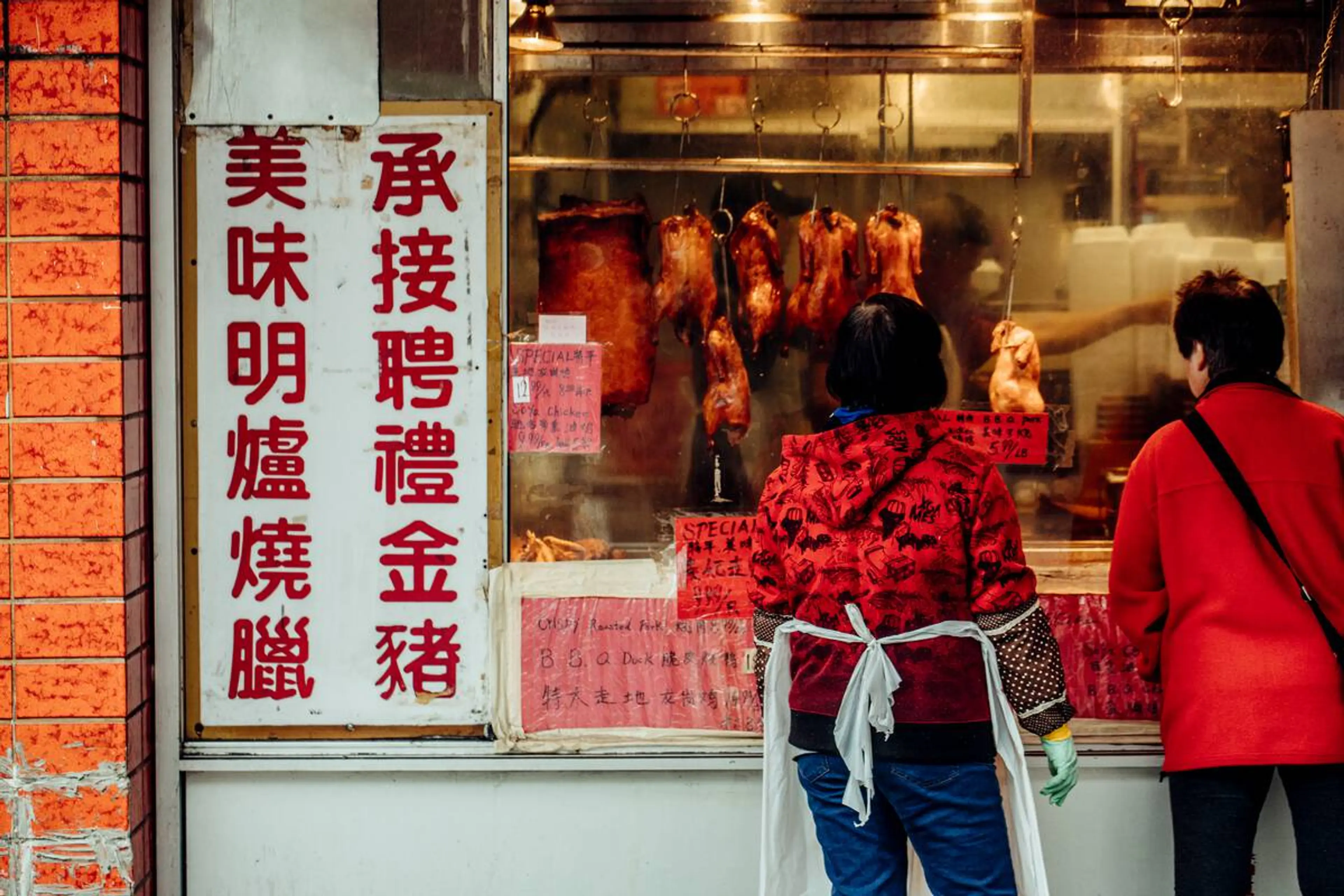 Customers look at BBQ meat in a Chinatown shop window