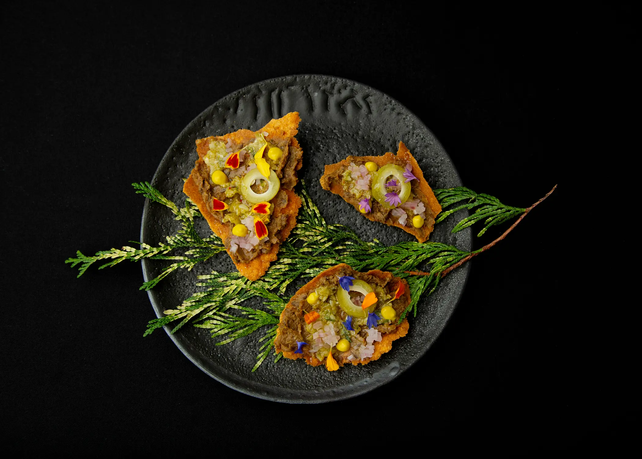 Lentil dish placed on pine branches and decorated with flowers at The Acorn restaurant in Vancouver.