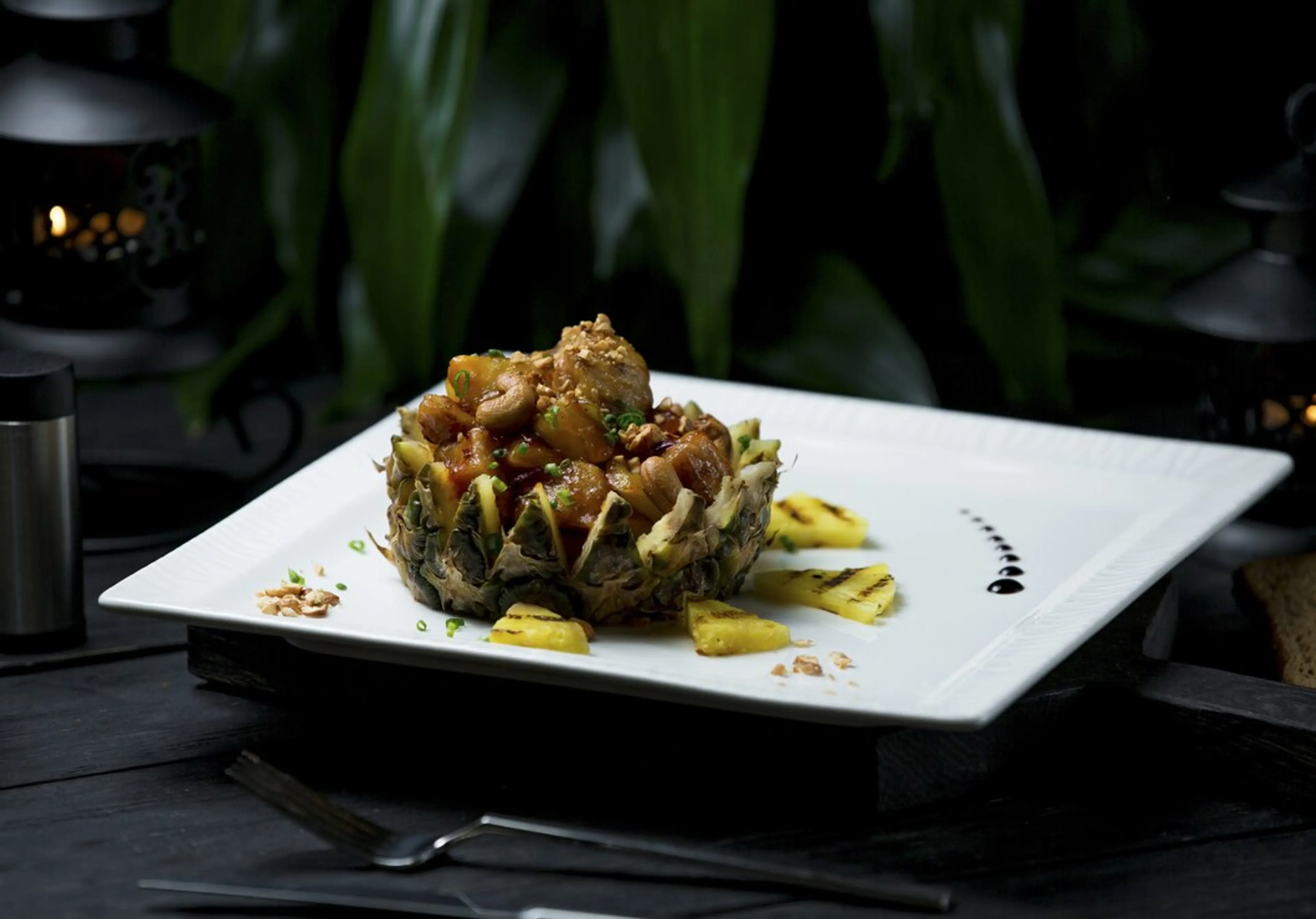 A gourmet dish served in a hollowed-out pineapple half, filled with a saucy meat and vegetable mixture, is garnished with pineapple pieces—a presentation you'd expect at top Vancouver restaurants or standout places to eat in Vancouver.