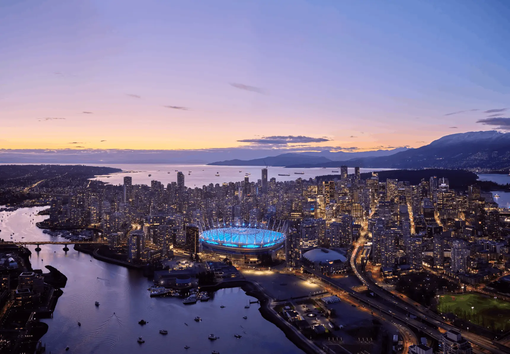 A stunning twilight view of the Vancouver skyline featuring the glowing BC Place stadium and the iconic geometric Science World dome reflecting on the calm waters of False Creek.