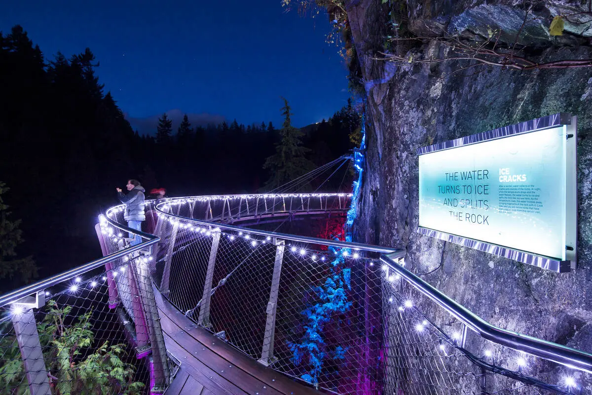 A cantilevered walkway at the Capilano Suspension Bridge Park lit up in holiday lights for the Canyon Lights event.