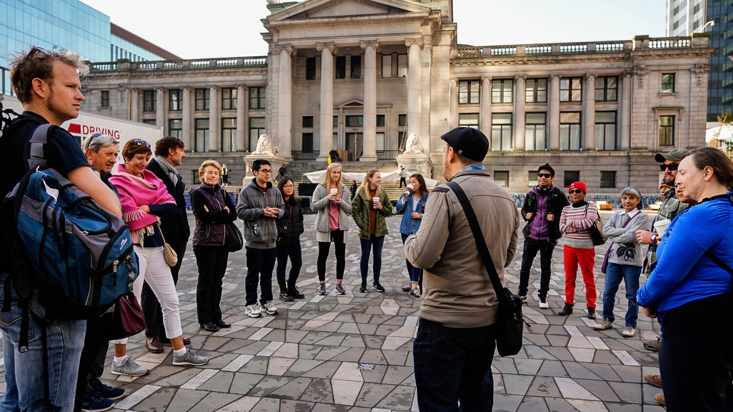 A group listens to a tour guide in front of the Vancouver Art Gallery