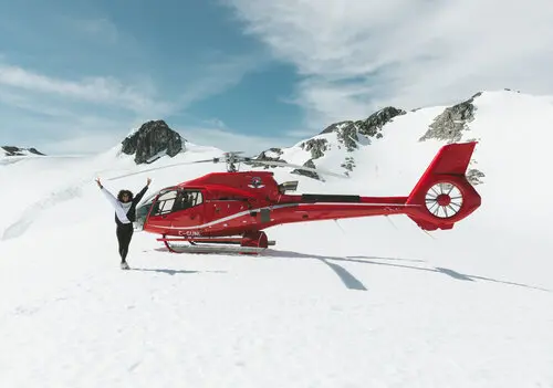 A helicopter landing on a snowy mountain near Whistler - Blackcomb Helicopers