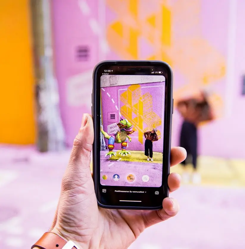 A person holds a phone screen that shows augmented reality art at the VMF Winter Arts Fest in Vancouver