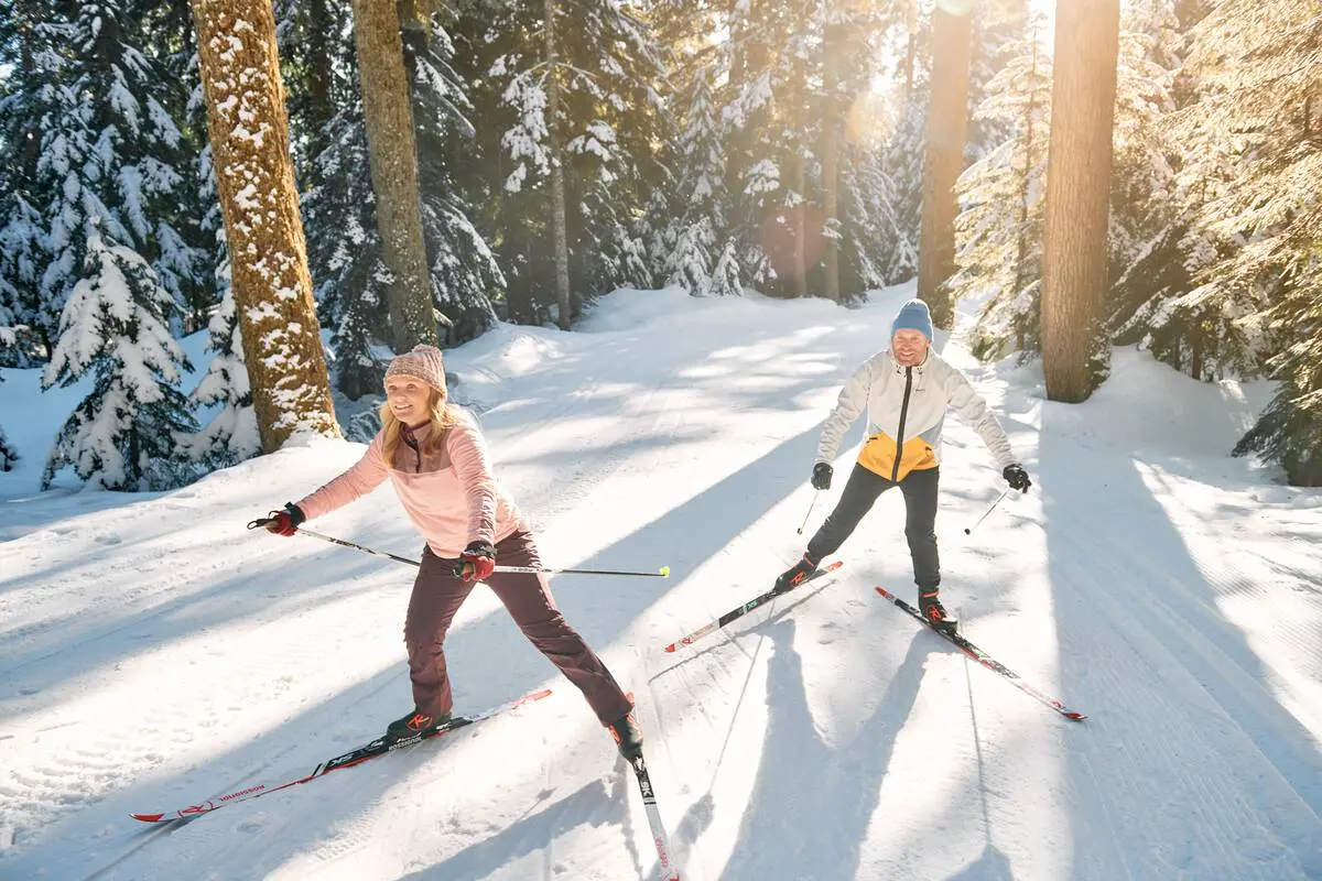 Two people cross country ski through a snowy forest at Cypress Mountain.