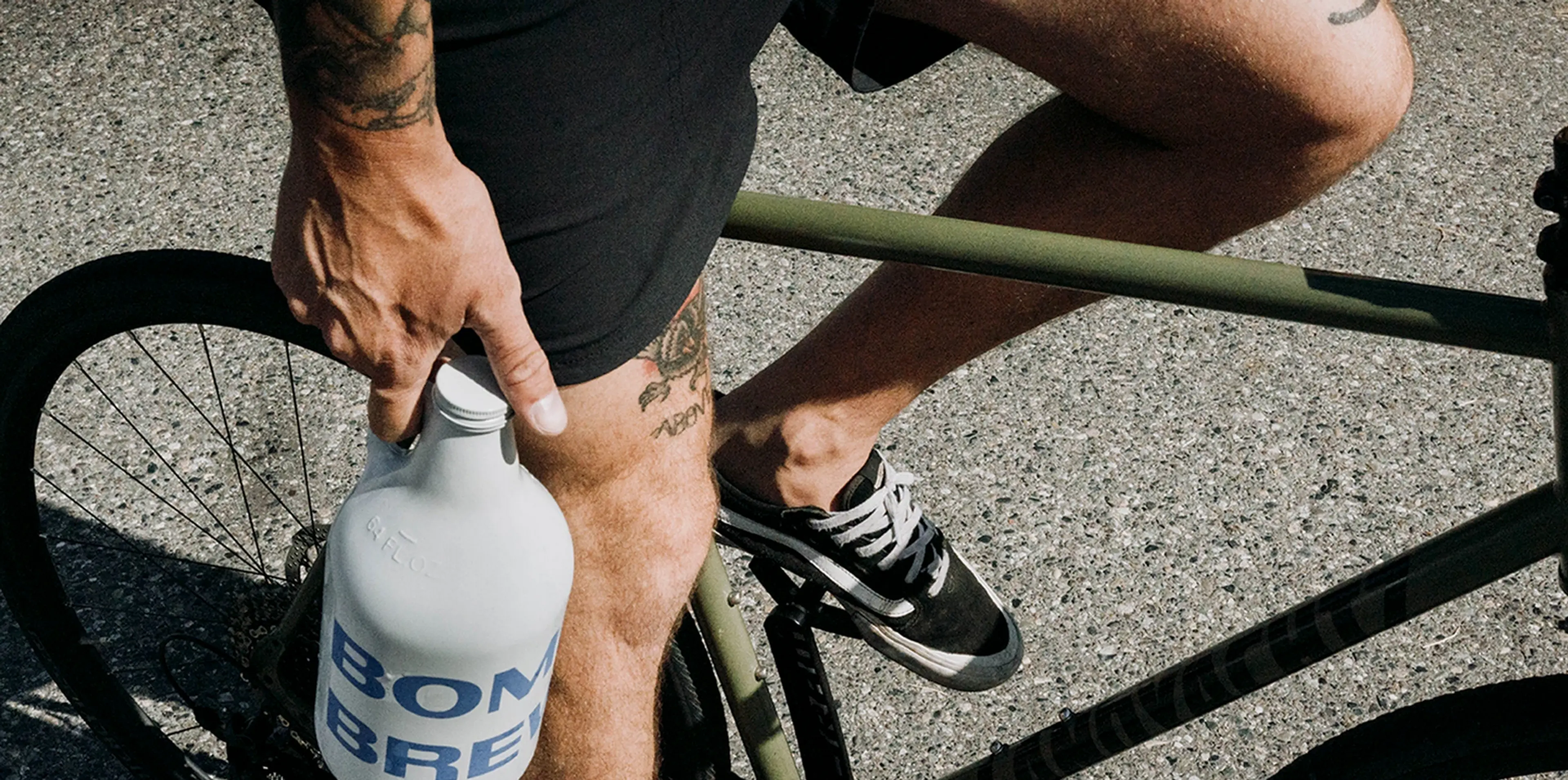 A cyclist holding a Bomber Brewing growler
