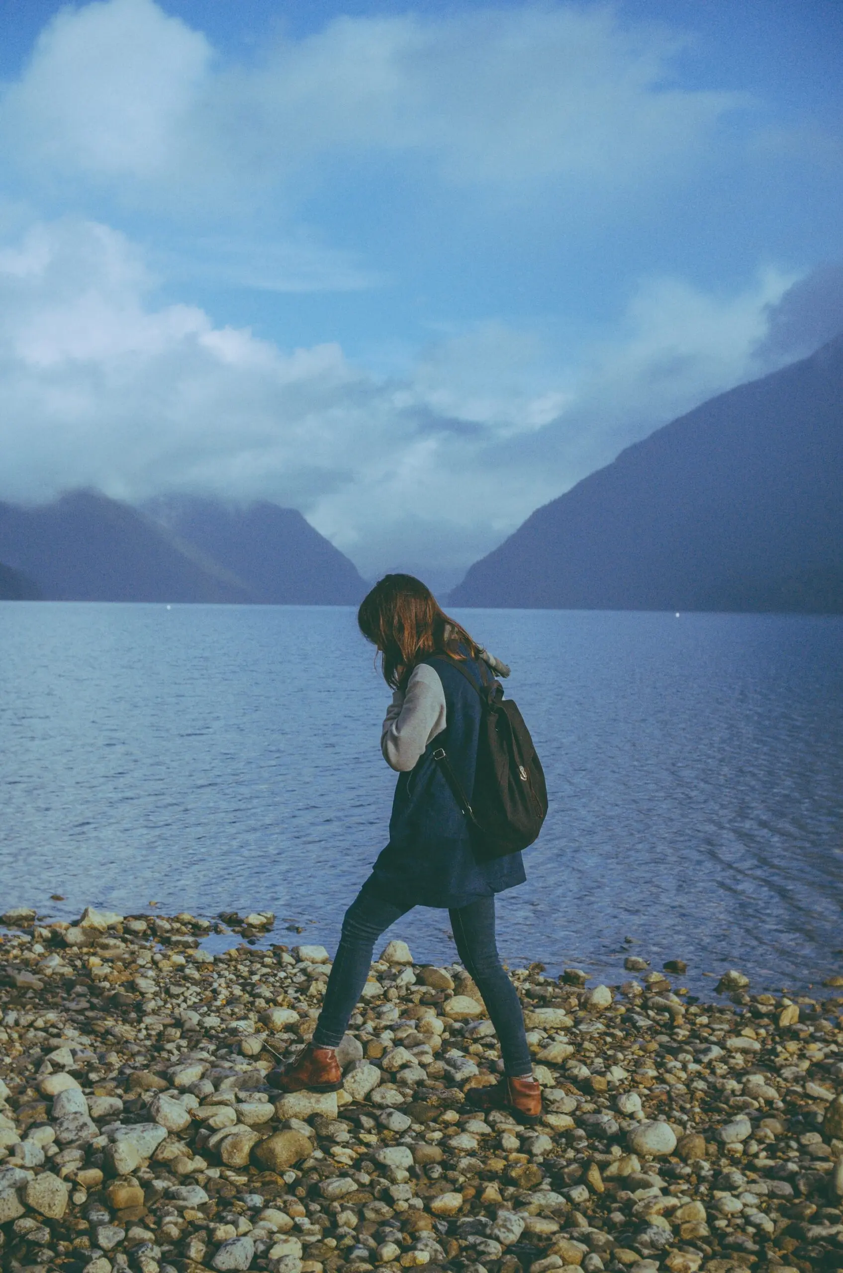 A woman walk along a gravel beach at Alouette Lake in Golden Ears Provincial Park