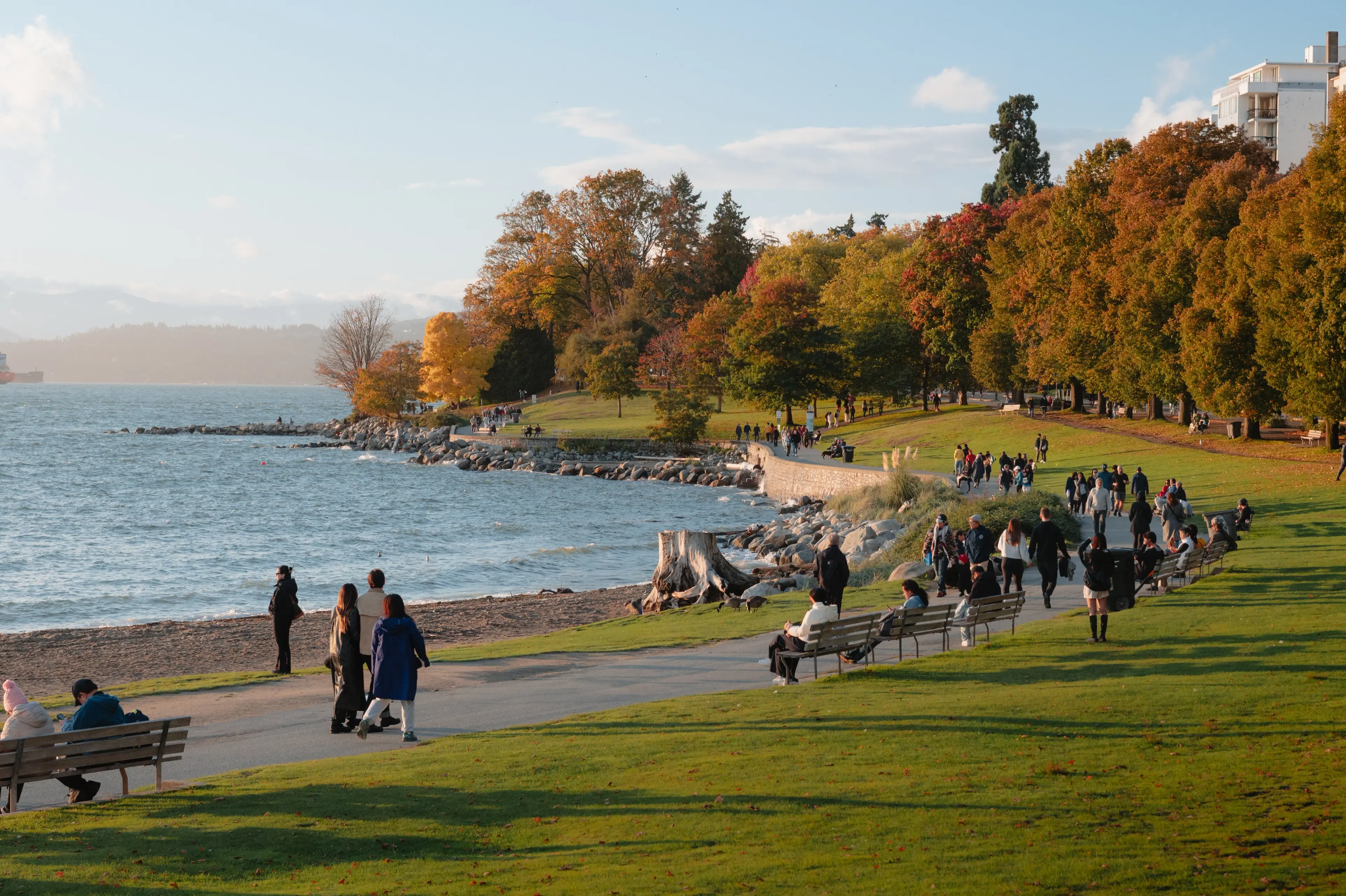 Wide shot of people walking along the sea wall at English Bay in Vancouver.