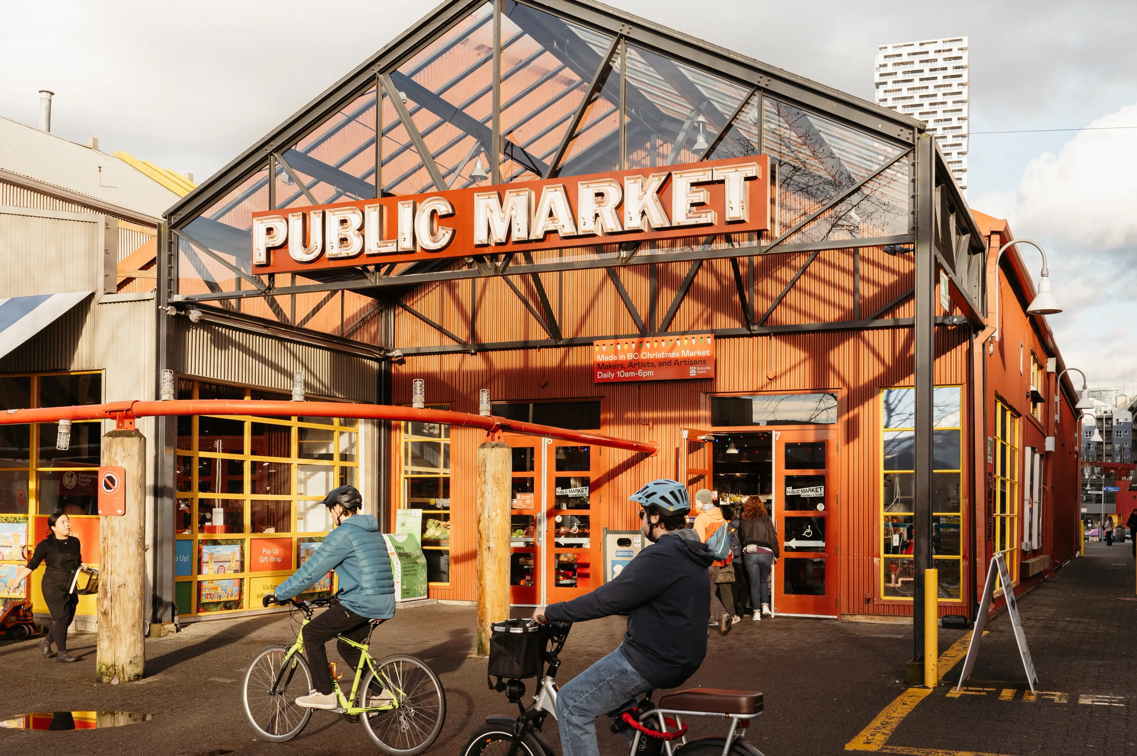 Two bikers pass the Granville Island building in Vancouver.