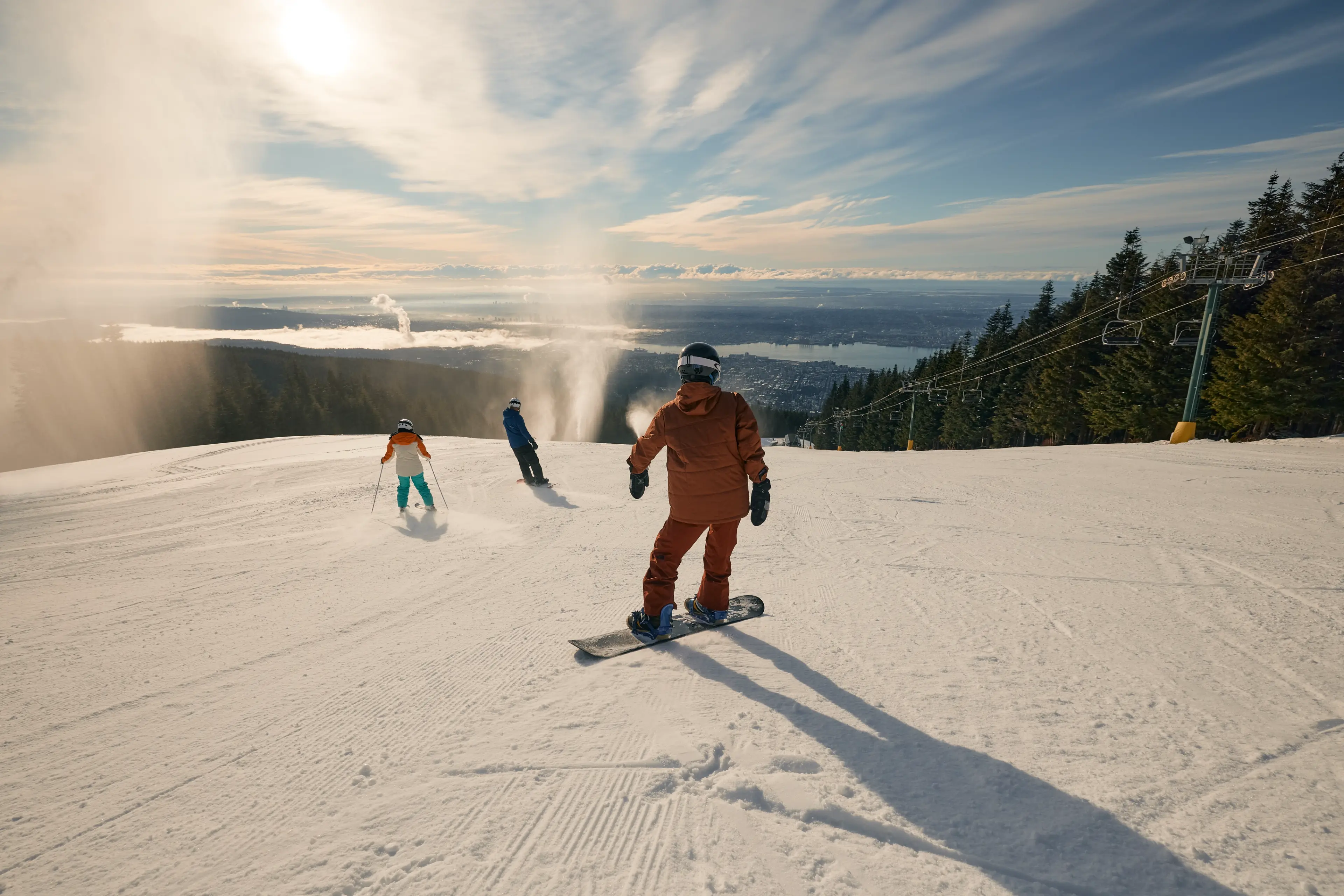 Snowboarders and skiers at Grouse Mountain on a sunny day