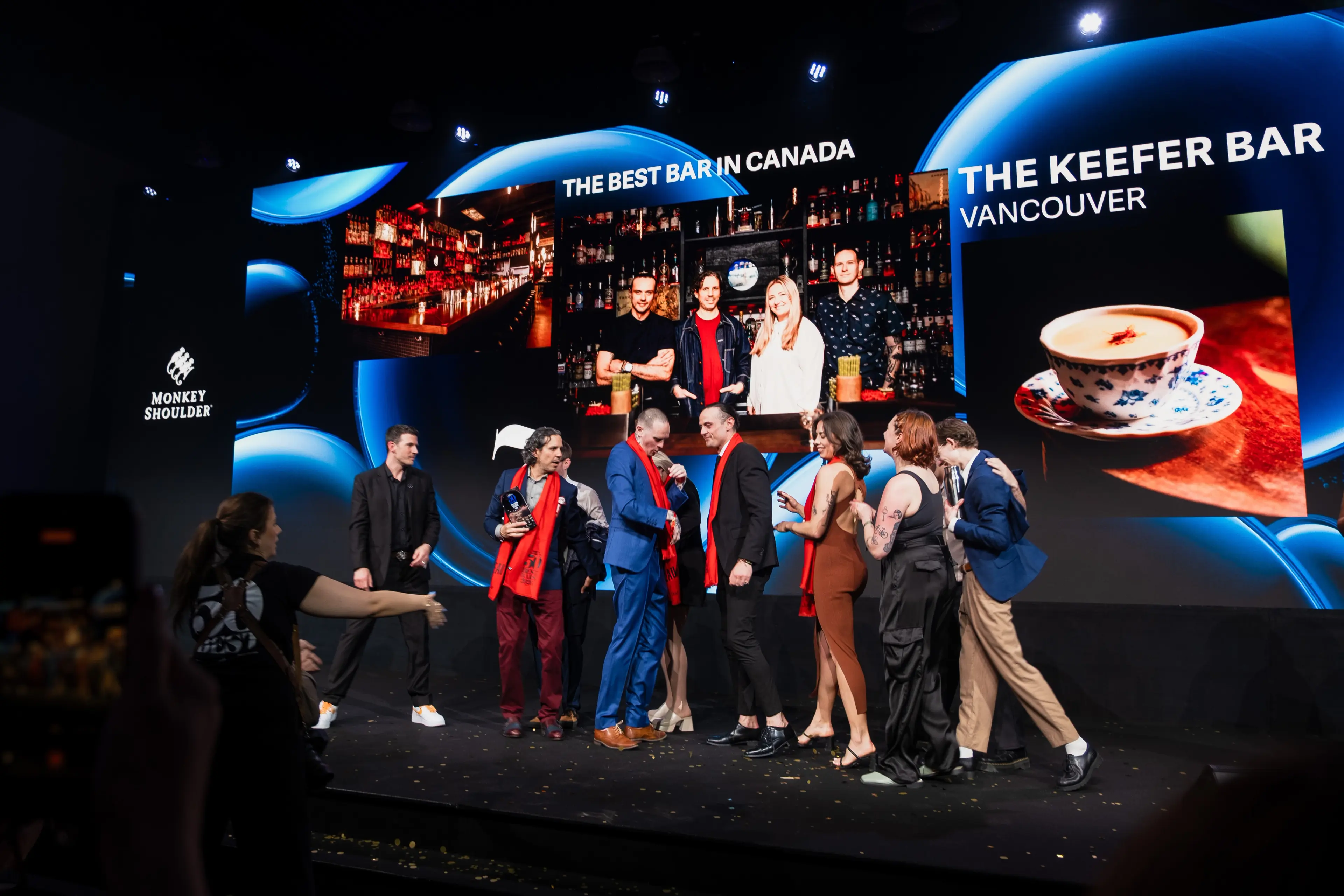 Group of people on stage at an event with large screens behind showing The Keefer Bar Vancouver and The Best Bar in Canada.
