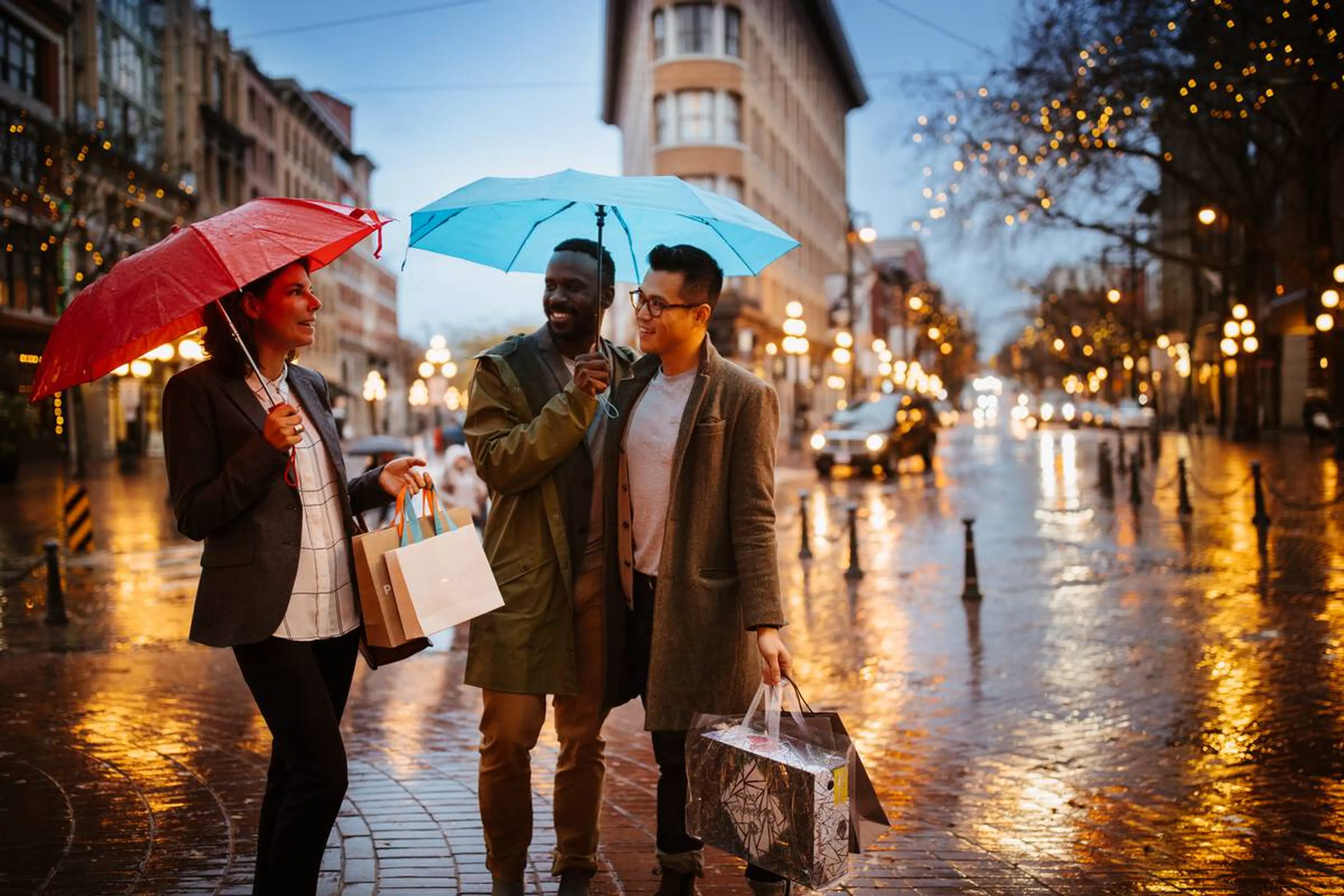 Three people with umbrellas shopping in Gastown.
