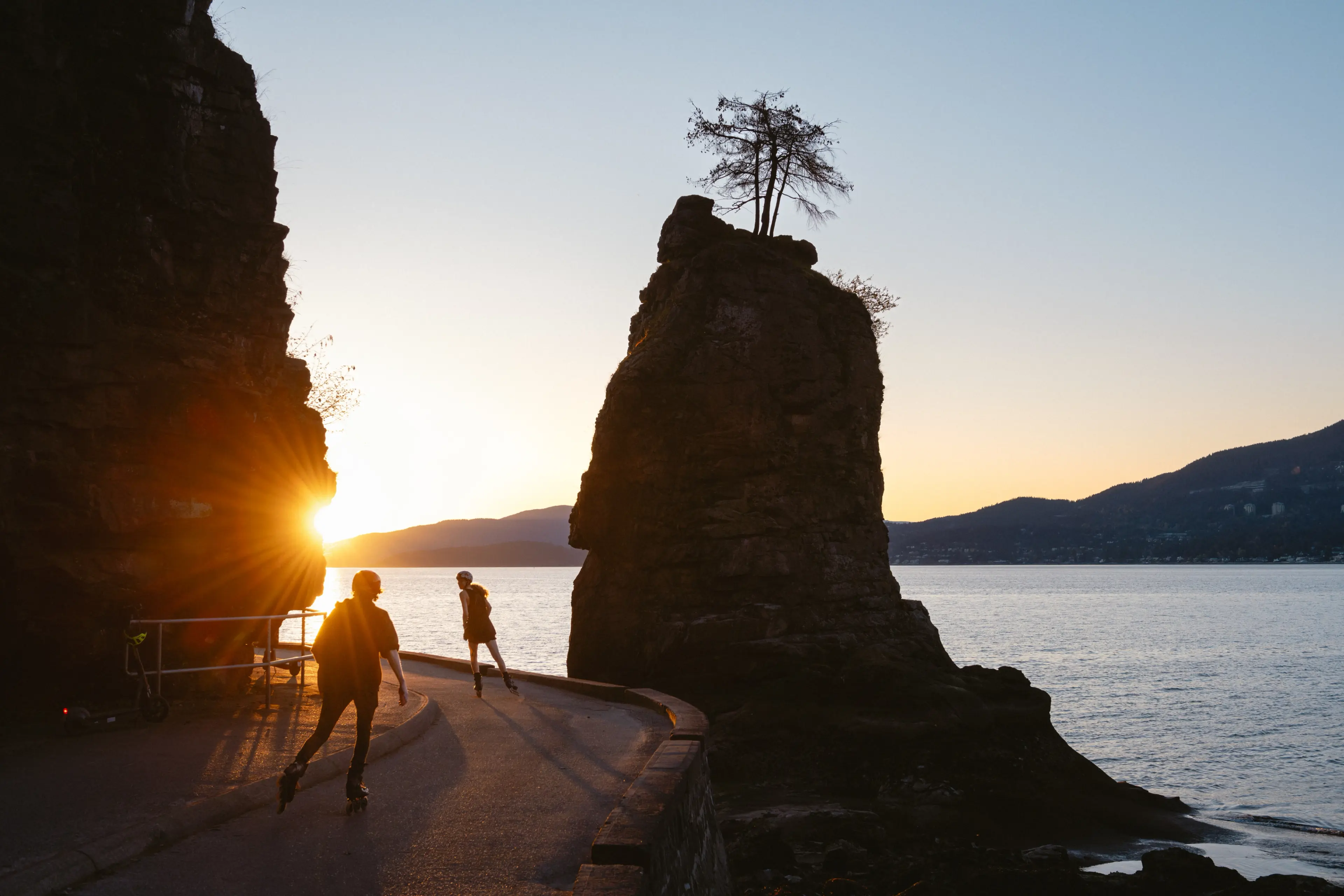 People on roller blades in Vancouver Stanley Park during sunset.