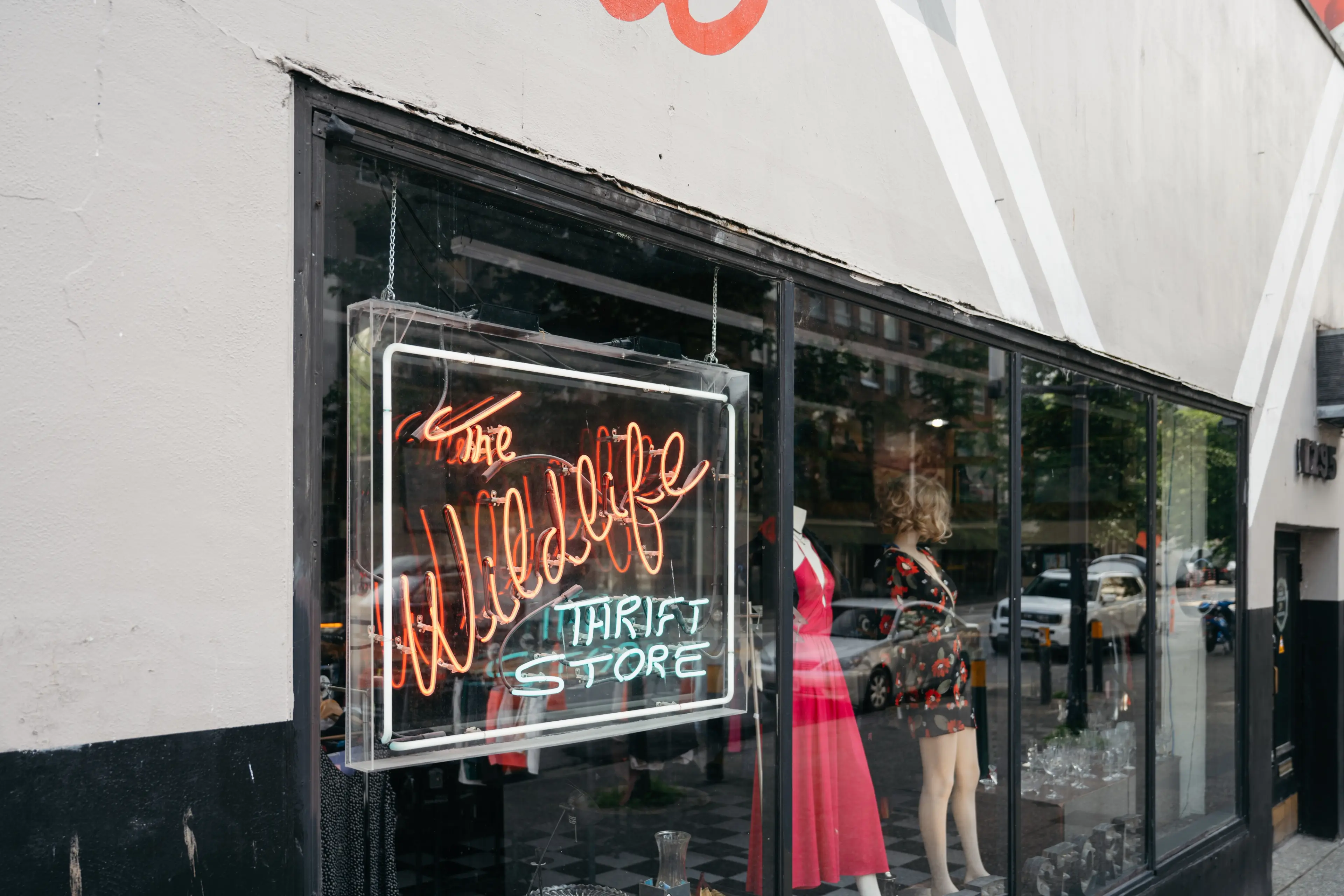 Close up of a neon sign and mannequins in the window at Wildlife Thrift Store in Vancouver.