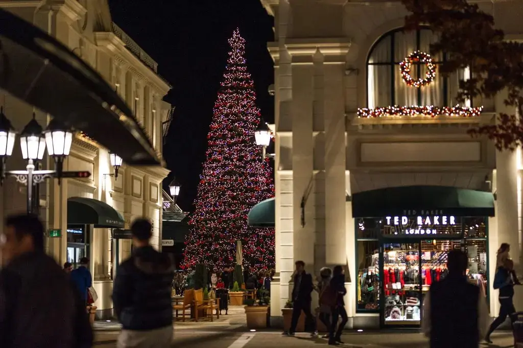A giant lit-up holiday tree stands between decorated shops at McArthur Glen Designer Outlet in Richmond.