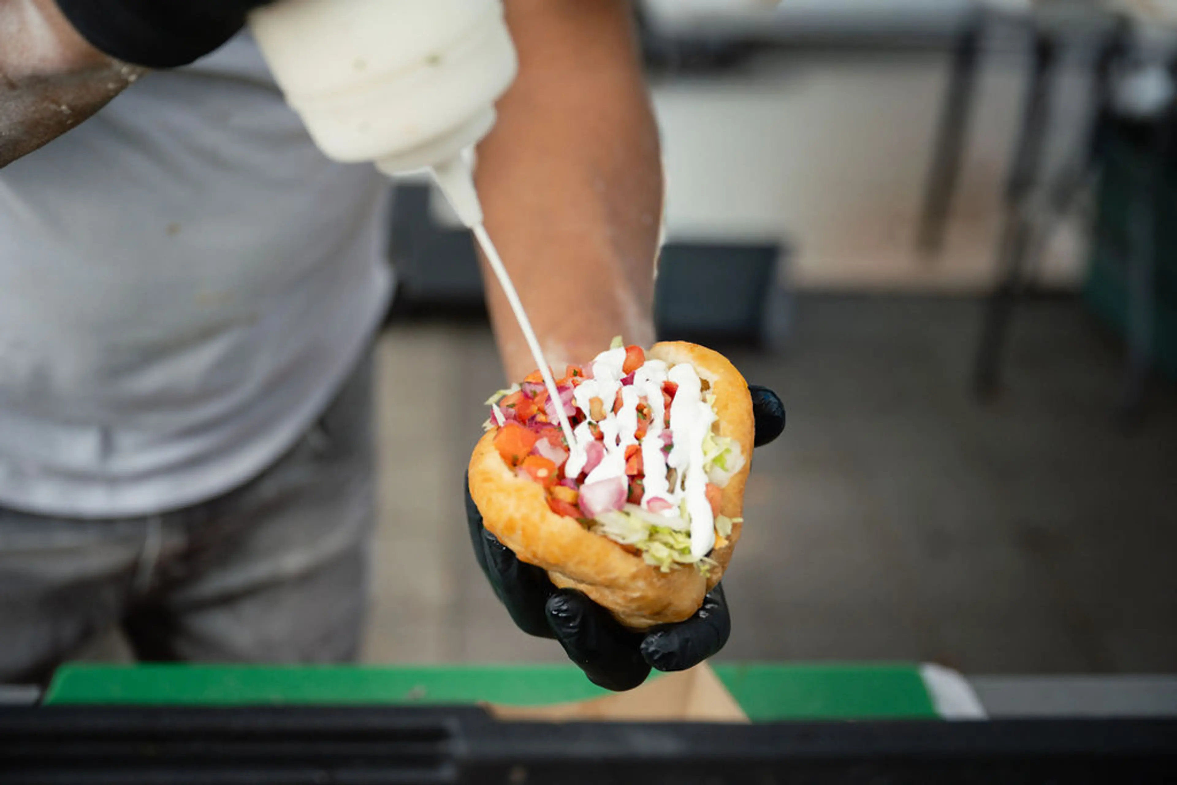 A hand pouring sauce over a filled bannock at West Coast Bannock in Vancouver.