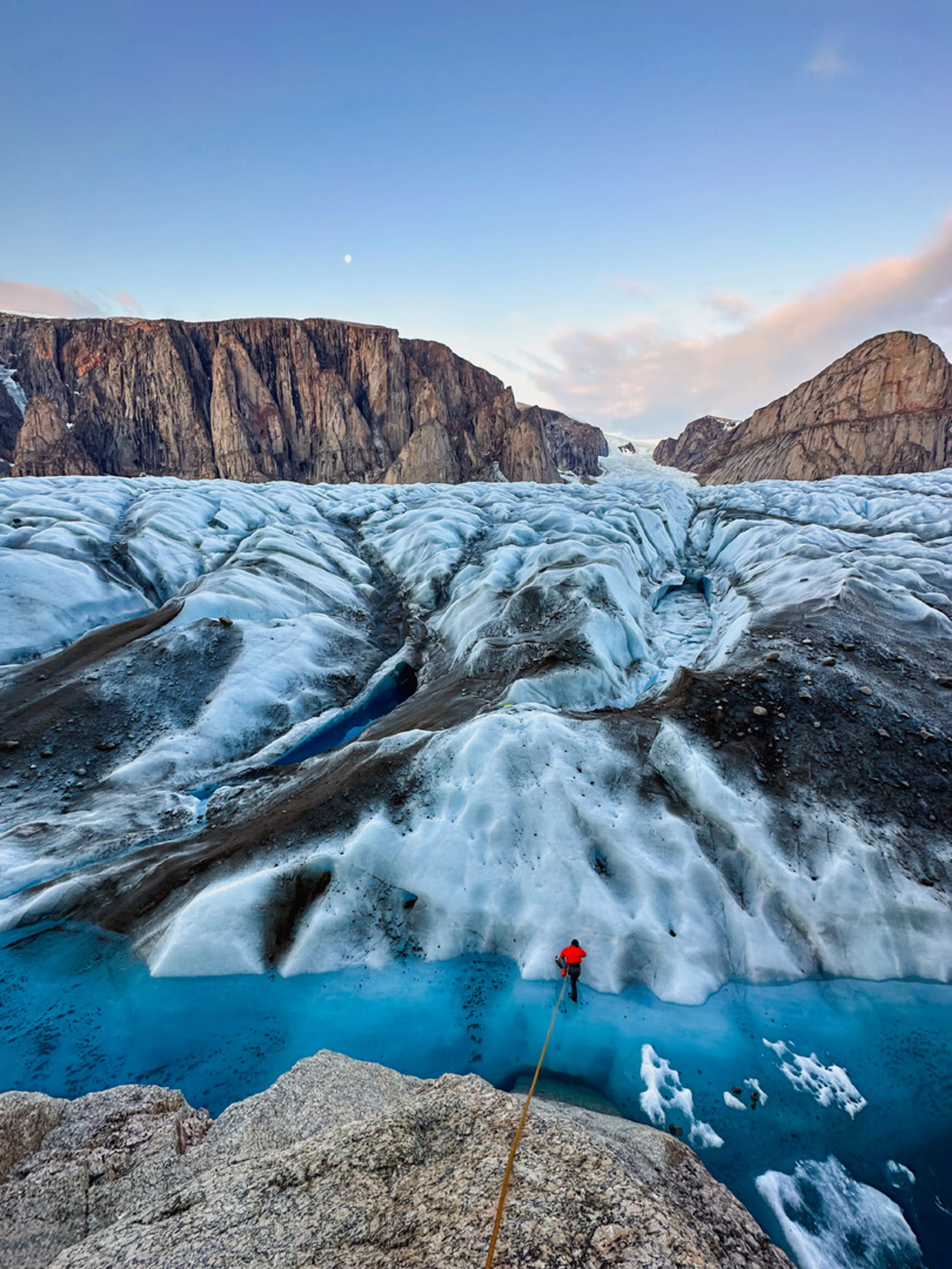 Still image from the film The Gnar-Whal's Odyssey showing a person crossing an icy channel in front of a glacier