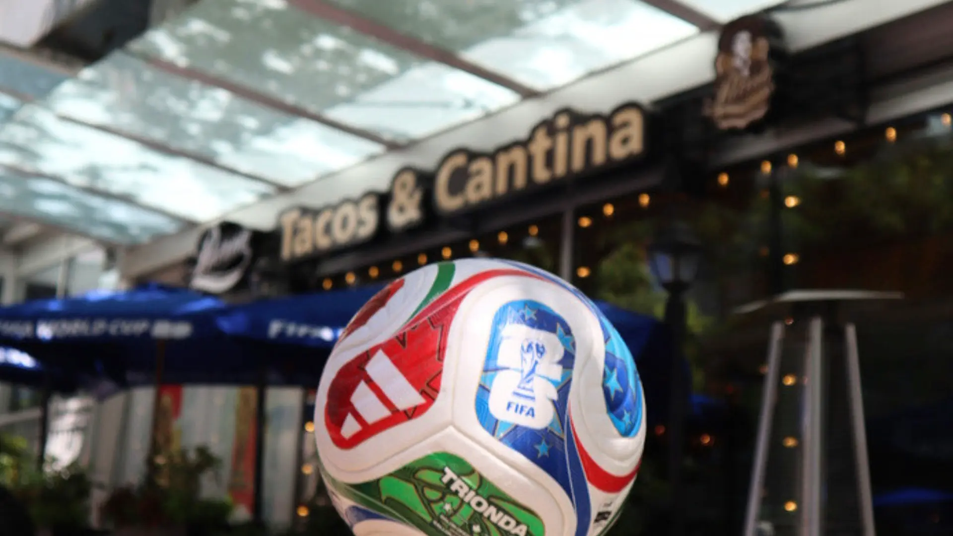 A colorful FIFA soccer ball in front of a restaurant with a sign reading Tacos & Cantina.