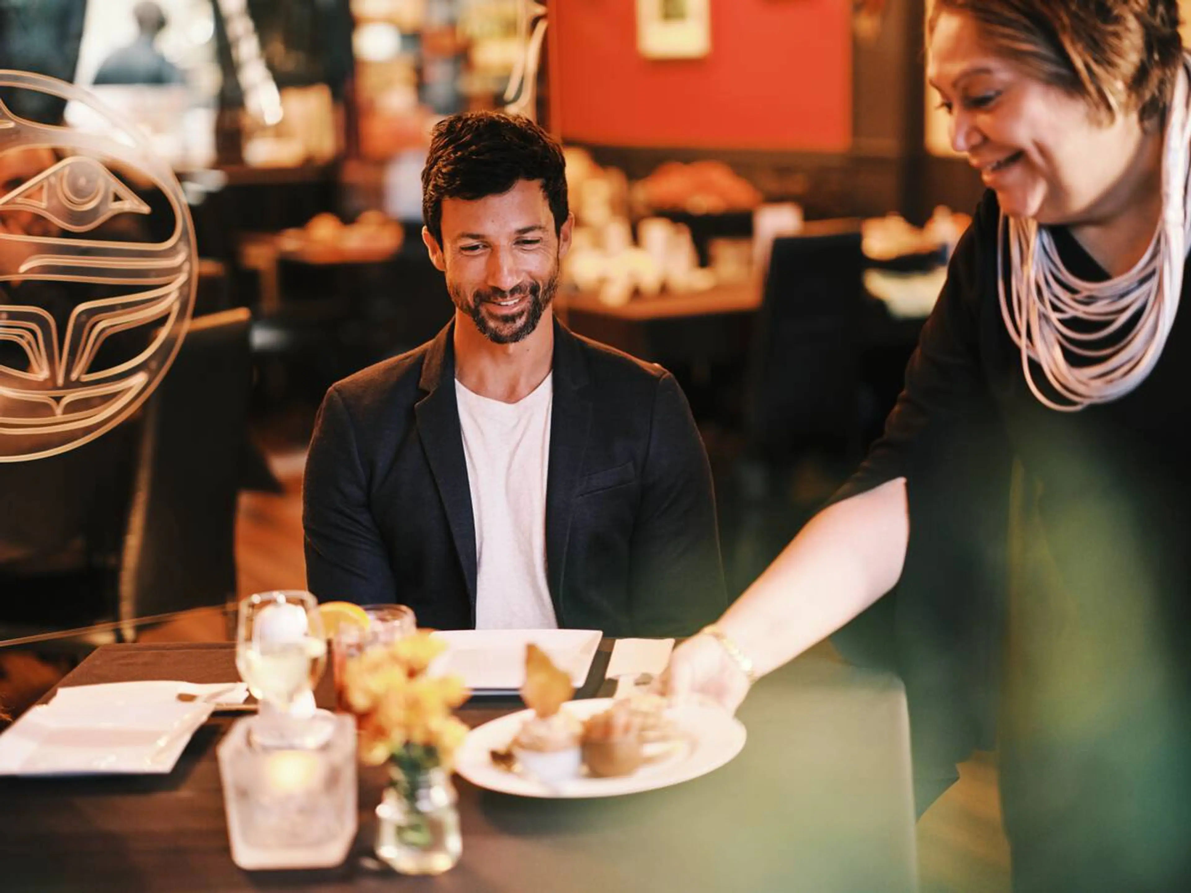 Inez Cook, the owner of Salmon n' Bannock in Vancouver, serves food to a couple at the restaurant.