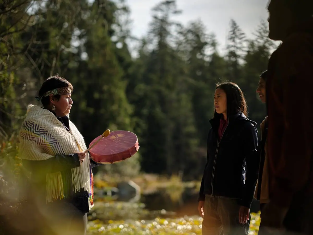 Candace Campo from Talaysay Tours is conducting a presentation and speaking to a group while on a walking experience in Stanley Park in Vancouver.